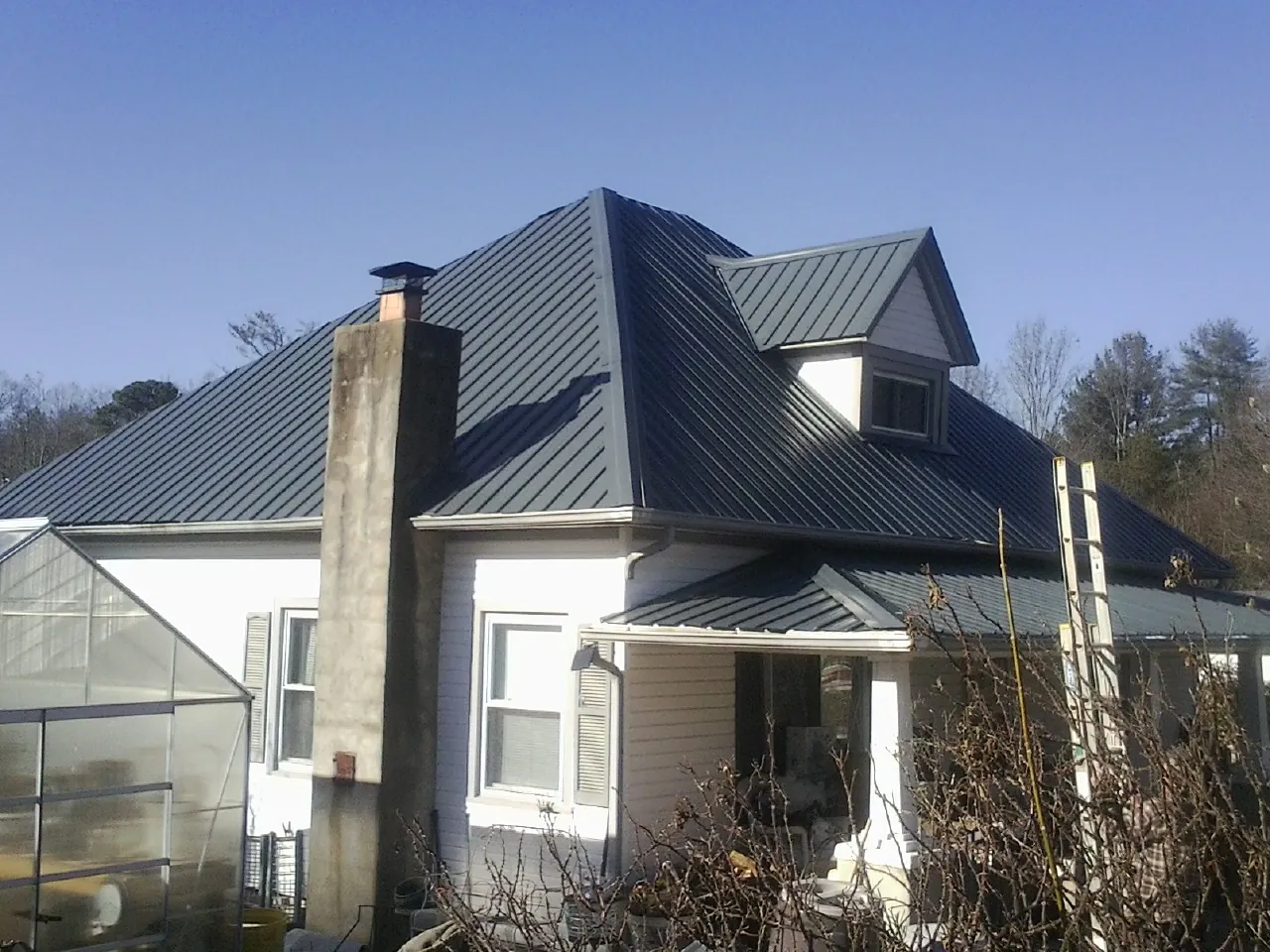 Dark blue standing seam metal roof on a white farmhouse with dormer — Slate & Tile Roof Repair by Roofing Brothers in Atco