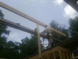 Carpenter setting a ridge beam over a new addition frame — Ice Dam Removal by Roofing Brothers in Atco