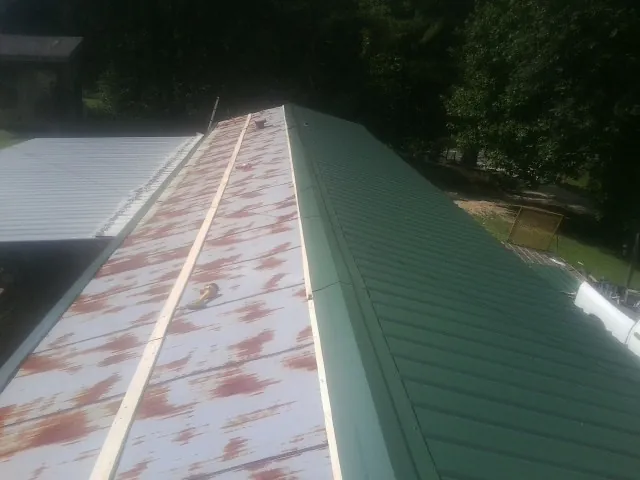 Old rusted panels beside newly installed green metal roofing — Wind Damage Roof Repair by Roofing Brothers in Atco