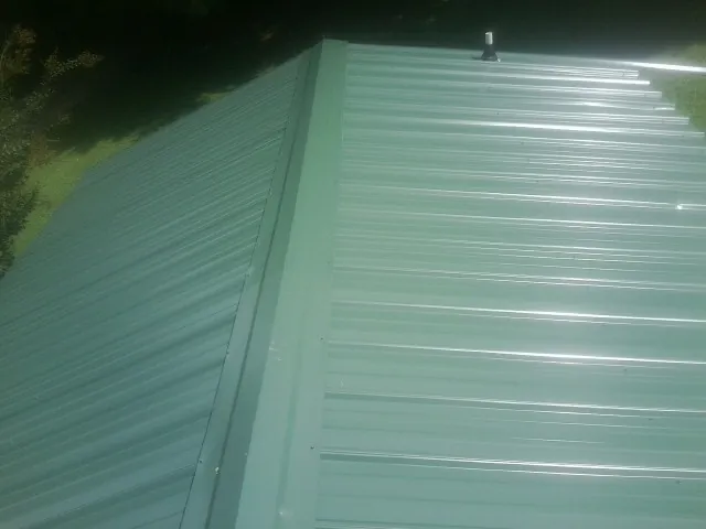 New green metal panels meeting at the ridge of a roof — Flat Roof Repair work by our crew in Atco