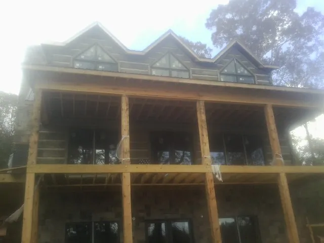 Dormers and porch framing on a large log home under construction — Roof Coating work by our crew in Atco