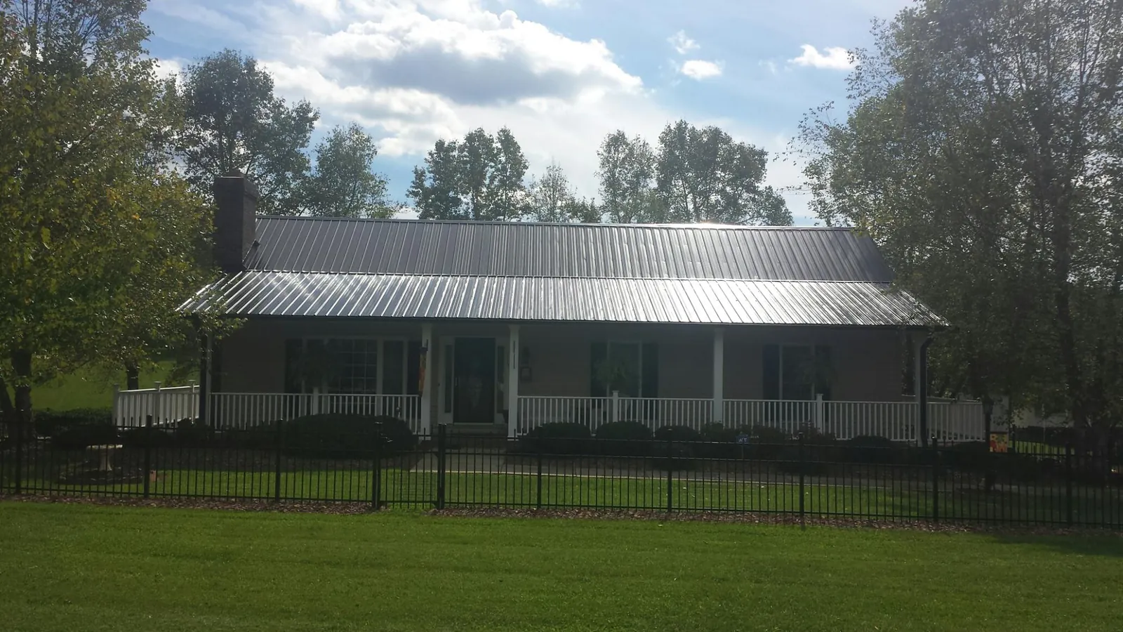 Gray metal roof on a brick ranch with a full width front porch — Gutter Guard Installation work by our crew in Atco