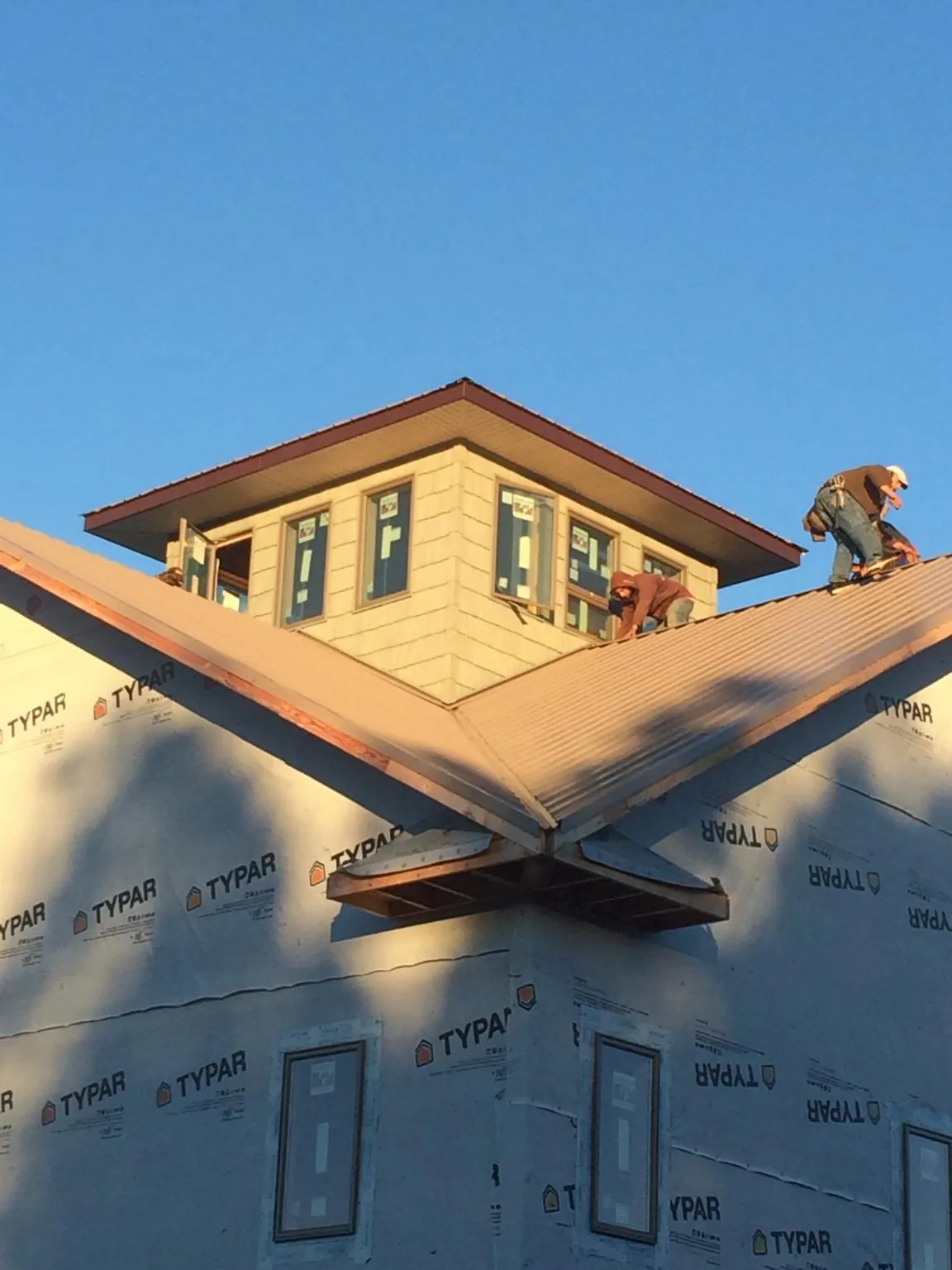 Roofers working around a rooftop cupola on a new metal roof at sunset — Roof Waterproofing in Atco by Roofing Brothers